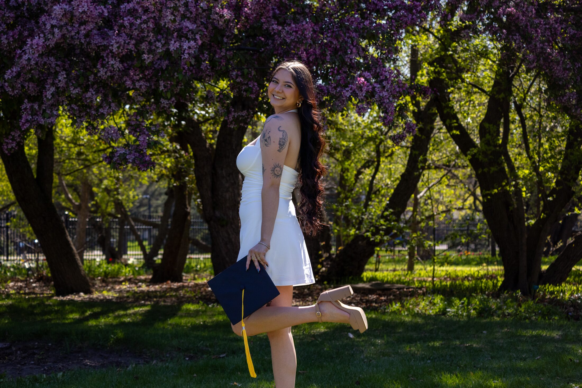 Playful graduation portrait beneath flowering trees