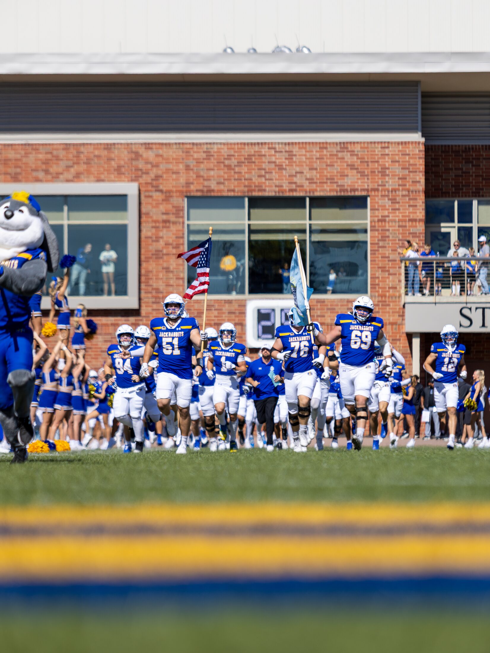 Football team entering the field with flags